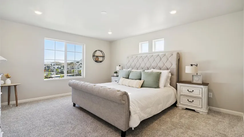 Light-filled bedroom featuring soft gray carpeting, recessed ceiling lighting, and a large multi-pane window
