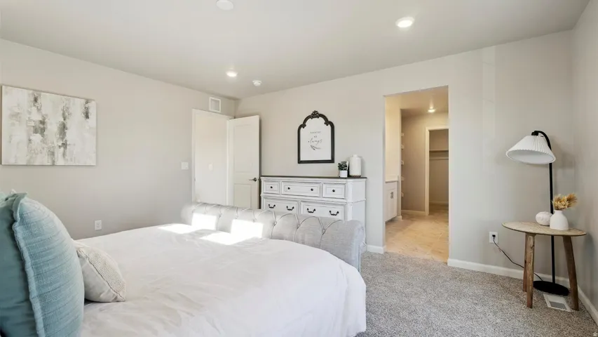 Plush carpeted bedroom with recessed lighting and a neutral wall color