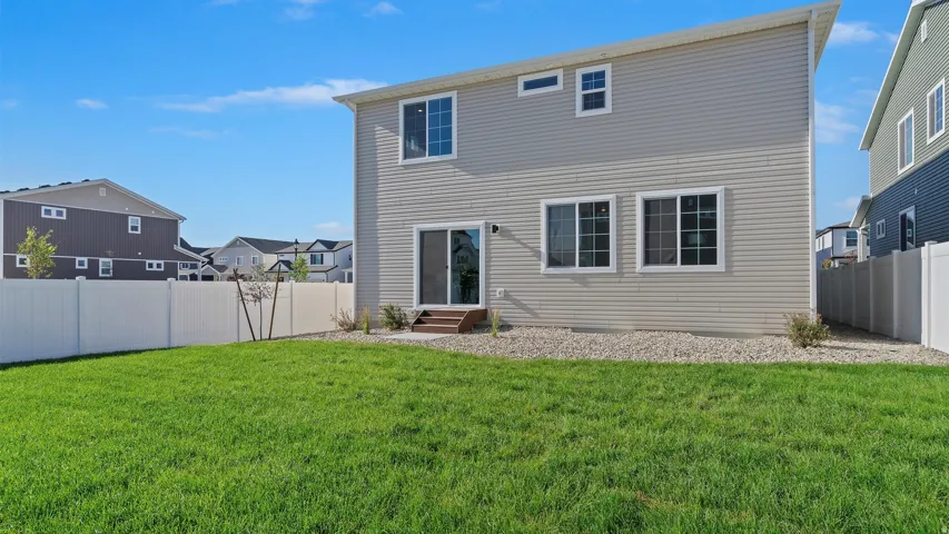 Expansive green lawn with a white vinyl fence enclosing the property