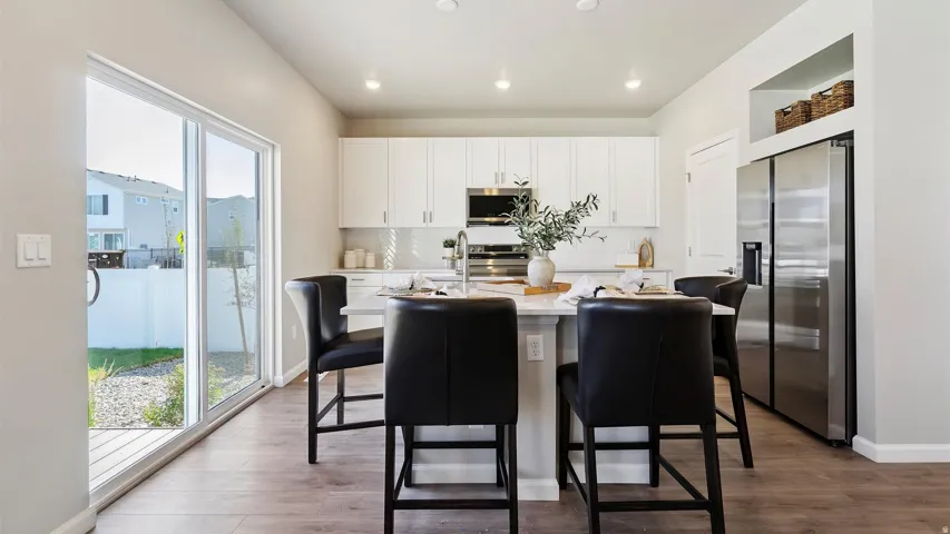 Kitchen with wood-finish flooring, white cabinetry, a built-in stainless steel refrigerator, and recessed lighting