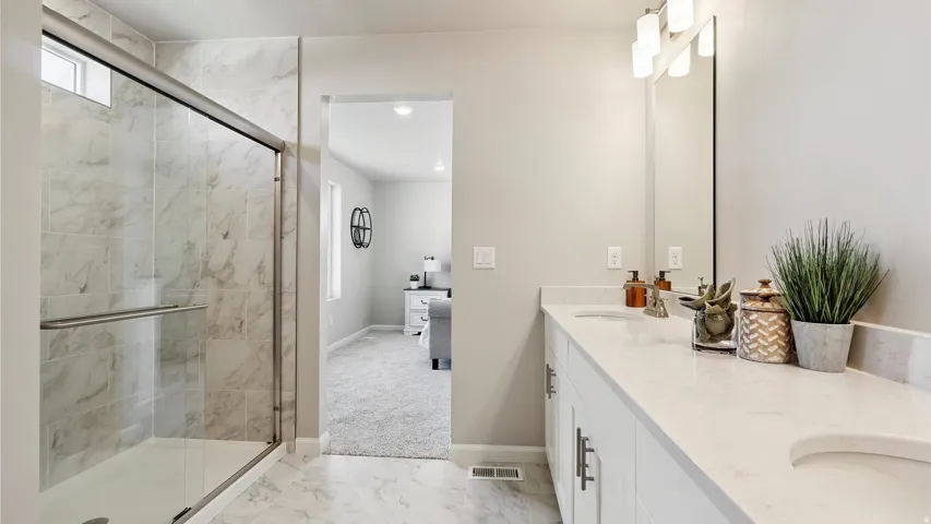 Dual vanity with integrated sinks, white cabinetry, and a full-width mirror