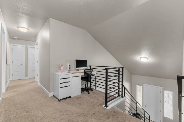 Upper-level hallway featuring a modern black metal railing, neutral carpeting, and contemporary ceiling light fixtures
