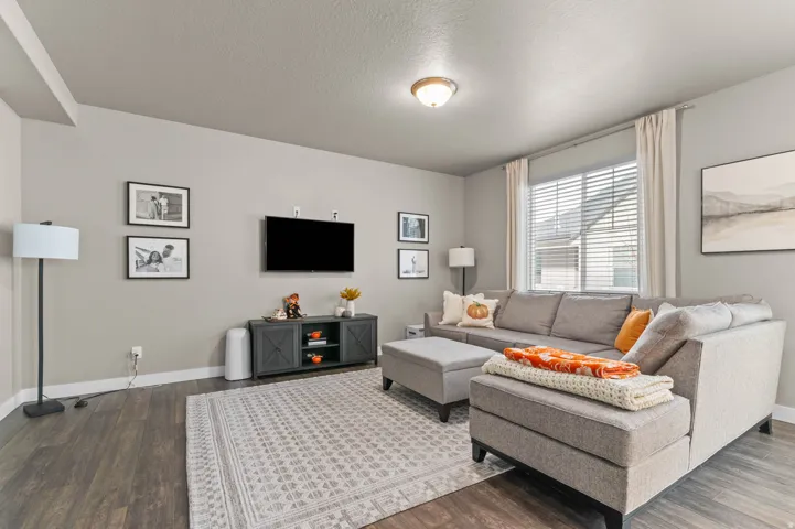 Living area featuring wood-finish flooring, light gray wall paint, and a window with blinds