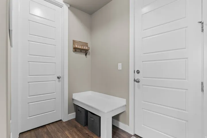 Entryway featuring rich wood-finish flooring, a built-in bench, and clean white trim