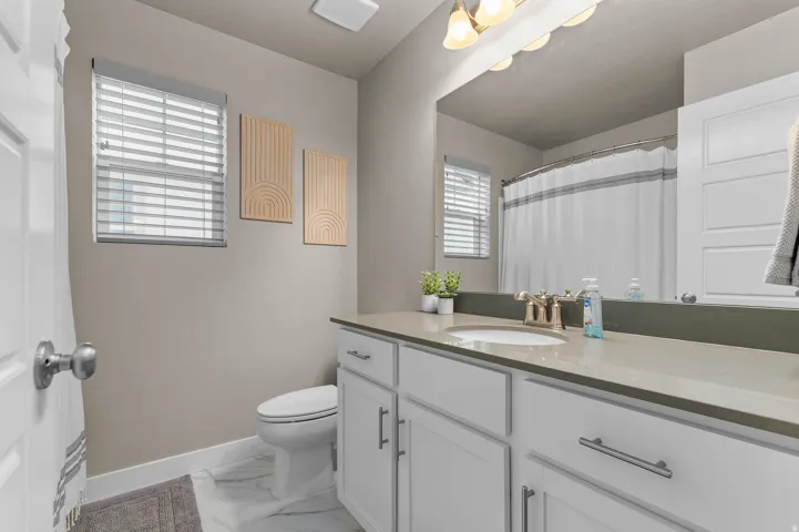 Main Bathroom featuring a single vanity with a light-toned countertop, white cabinetry with brushed nickel hardware, and an undermount sink