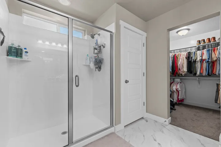 Glass-enclosed shower with white paneling and a transom window