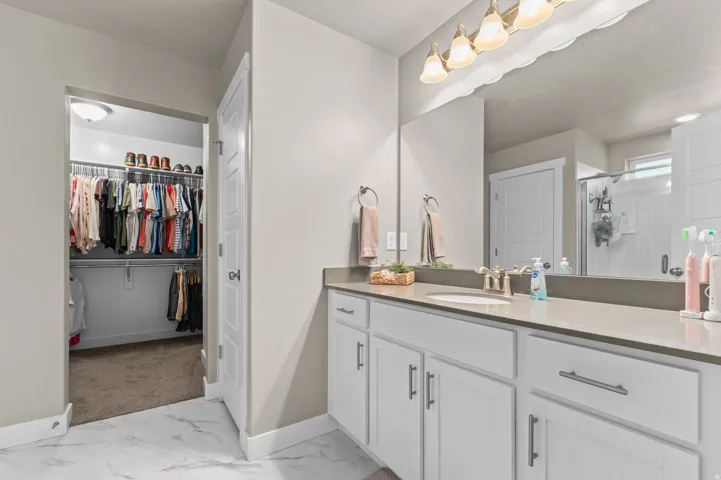 Primary Bathroom vanity, light-toned countertop, and white cabinetry