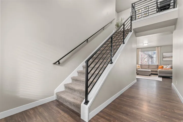 Staircase featuring carpeted treads, metal balusters, and a black handrail