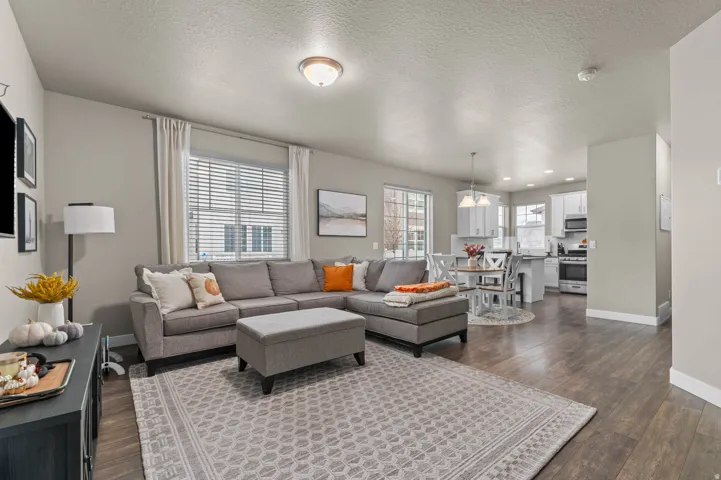 Open-concept living area featuring wood-finish flooring, recessed lighting, and large windows with blinds