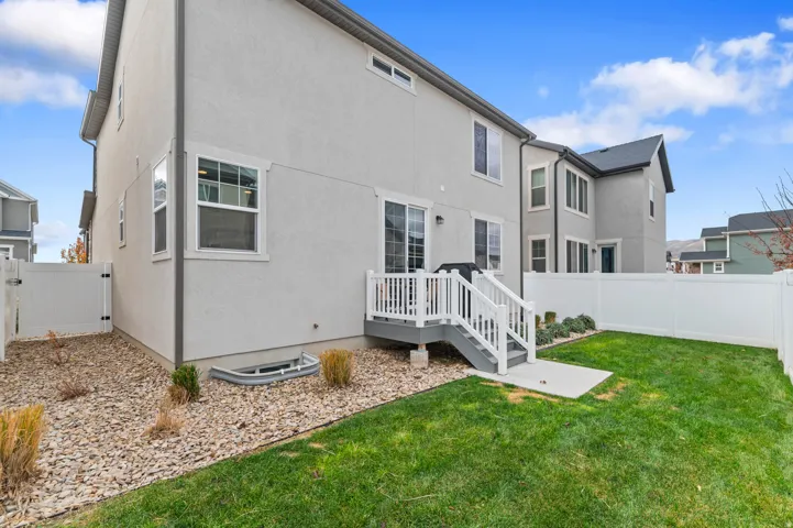 Private backyard featuring a manicured lawn, white vinyl fencing, and a multi-level deck with stairs