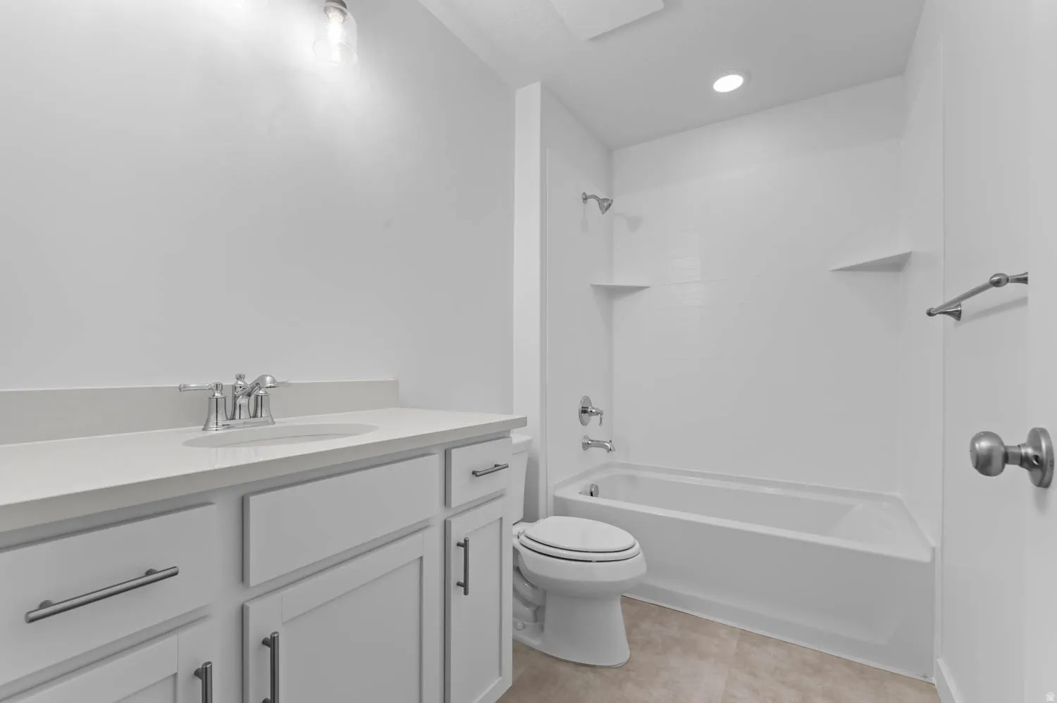 Bathroom featuring a white vanity with a light-colored countertop, chrome fixtures, and a white tub/shower combination