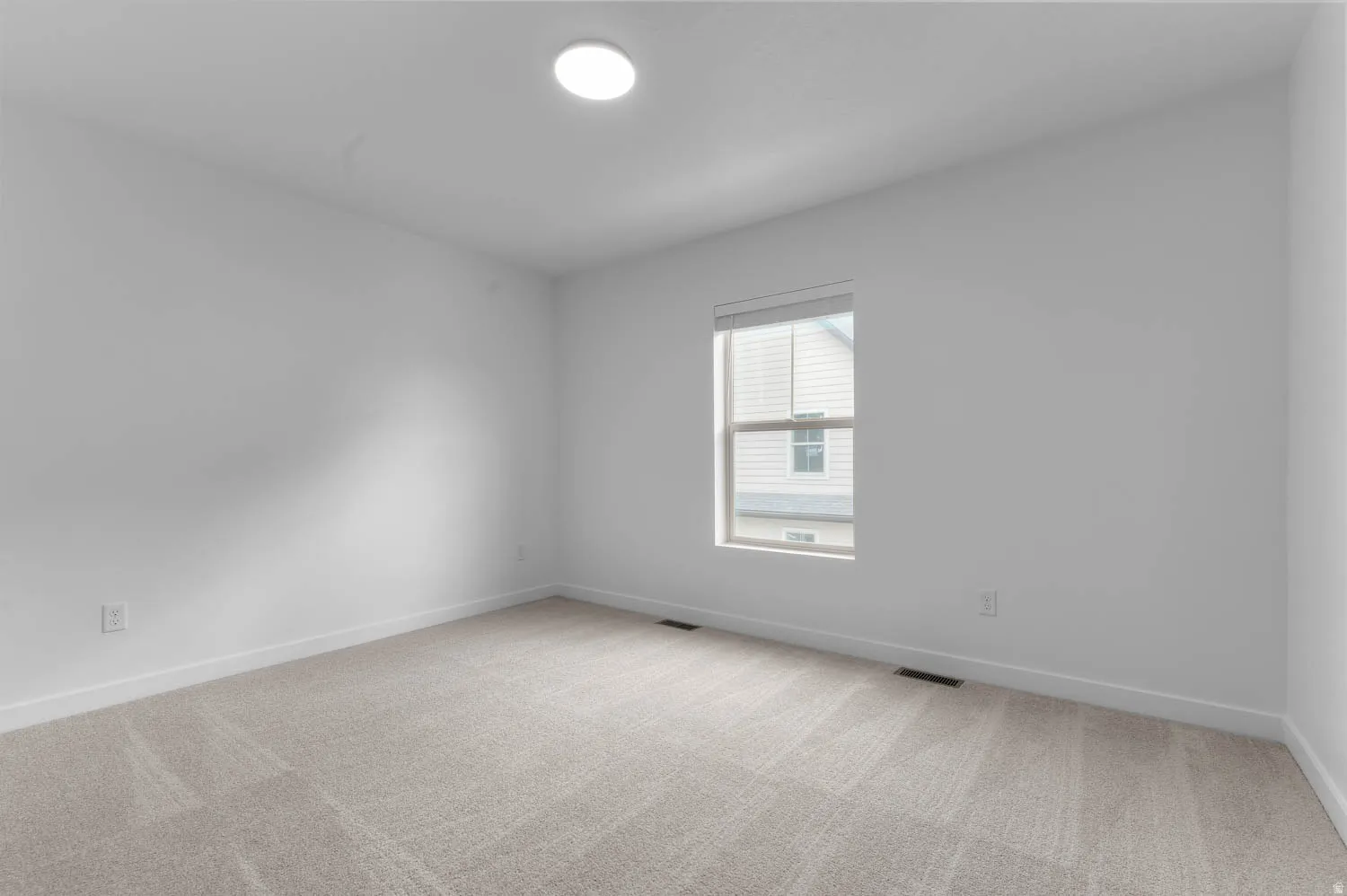 Room featuring neutral carpet flooring, white walls, a single window with blinds, and an overhead flush-mount light fixture