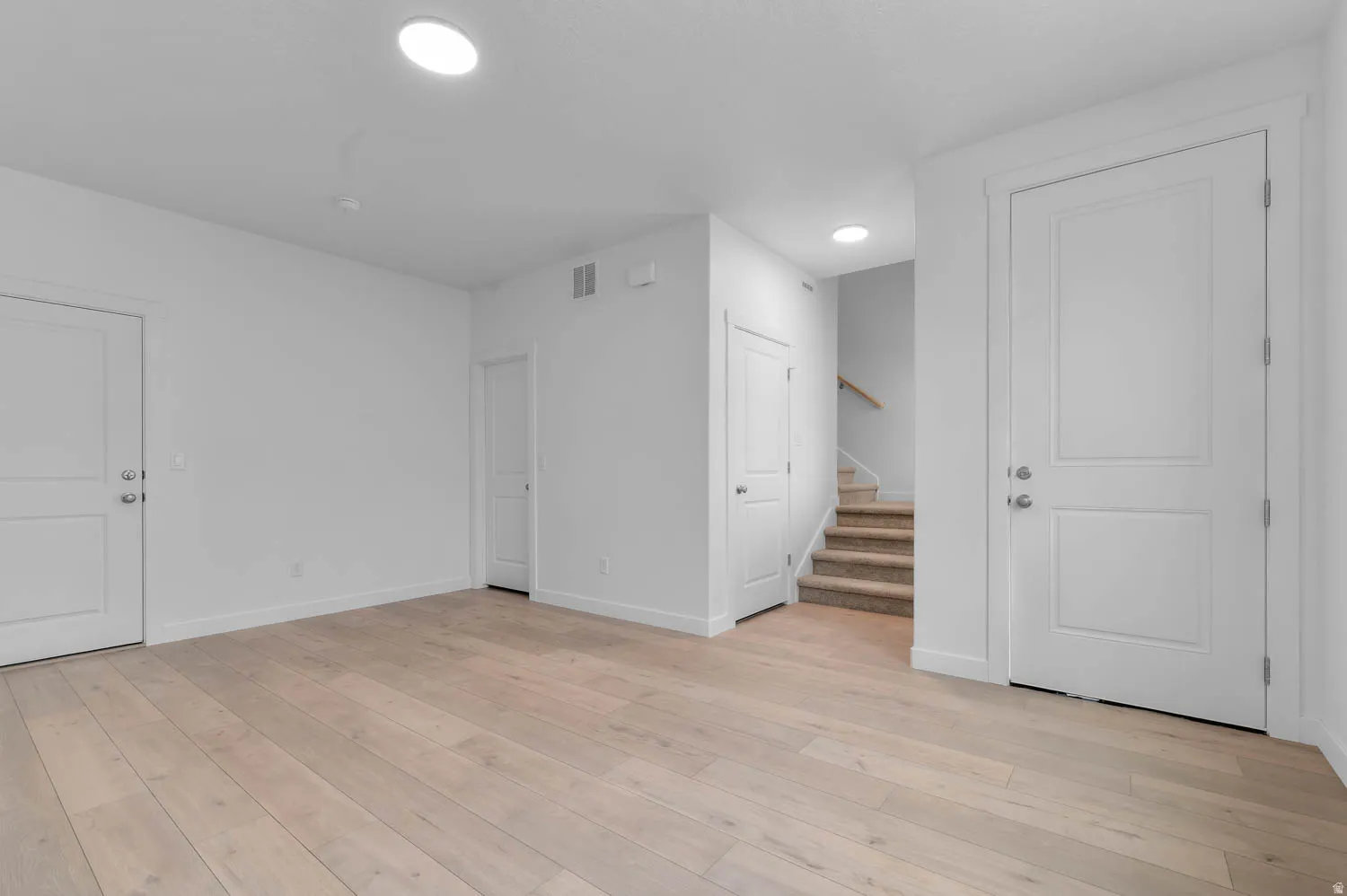 Expansive room featuring light wood-finish flooring, recessed lighting, and white baseboards
