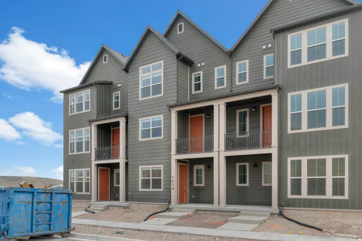 Modern multi-story facade featuring dark gray siding and prominent white-framed windows