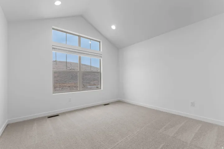 Vaulted ceiling room featuring a large window with transom, recessed lighting, and light-toned carpeting