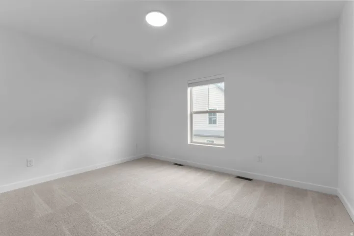 Room featuring neutral carpet flooring, white walls, a single window with blinds, and an overhead flush-mount light fixture