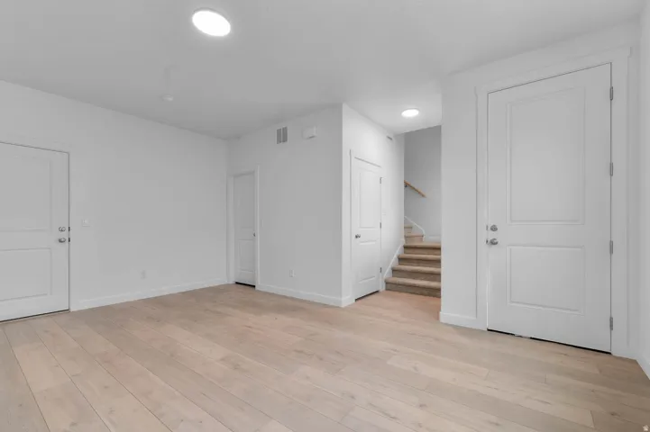 Expansive room featuring light wood-finish flooring, recessed lighting, and white baseboards