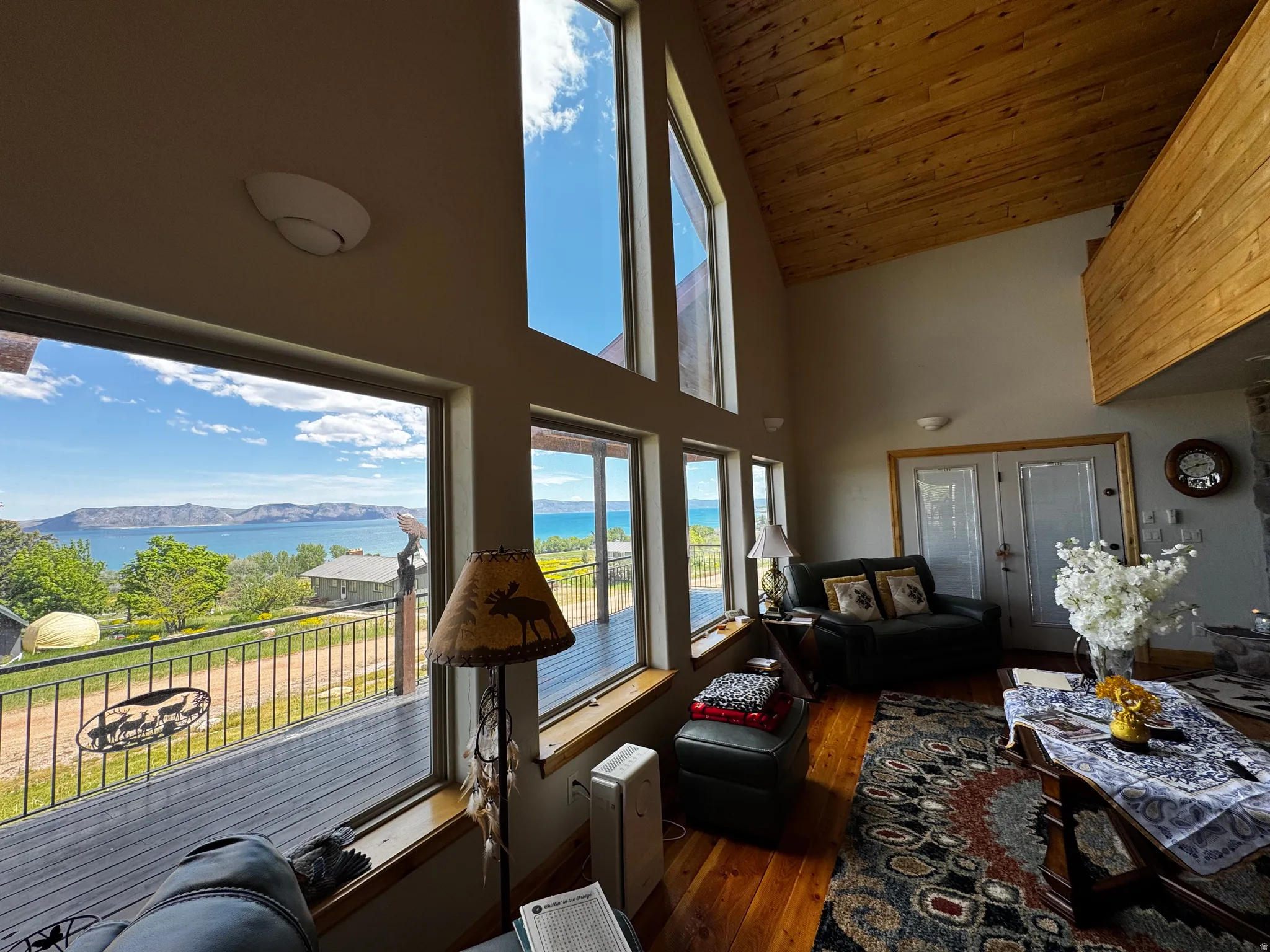 Spacious living area featuring expansive picture windows, wood-finish flooring, and an elevated wood-paneled ceiling
