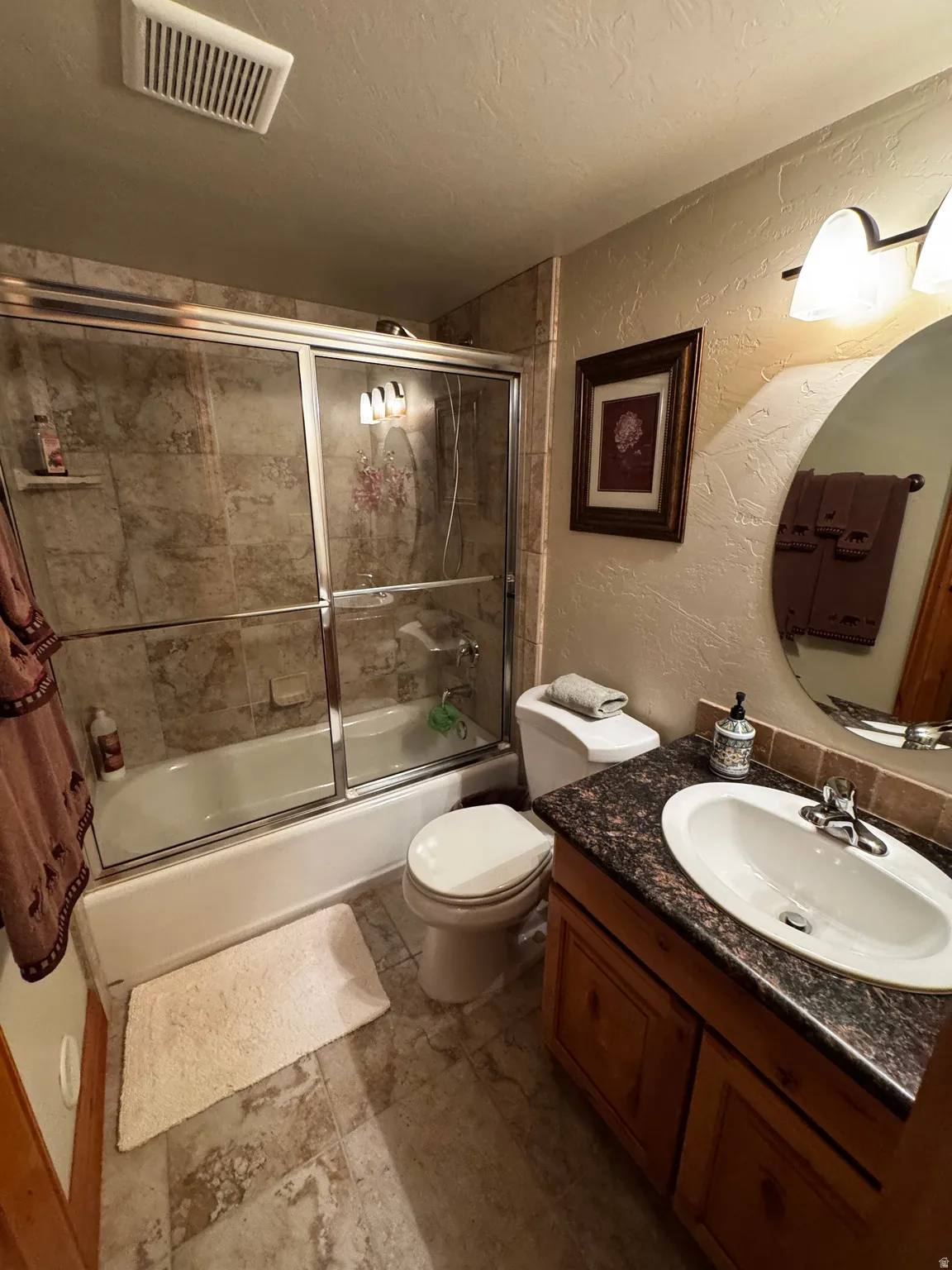 Bathroom featuring a combination bathtub and shower with tiled surround and glass sliding doors