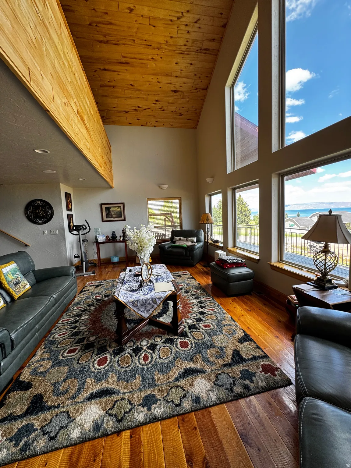 Living area featuring soaring vaulted ceilings with wood-finish panels, expansive picture windows, and wood-finish flooring