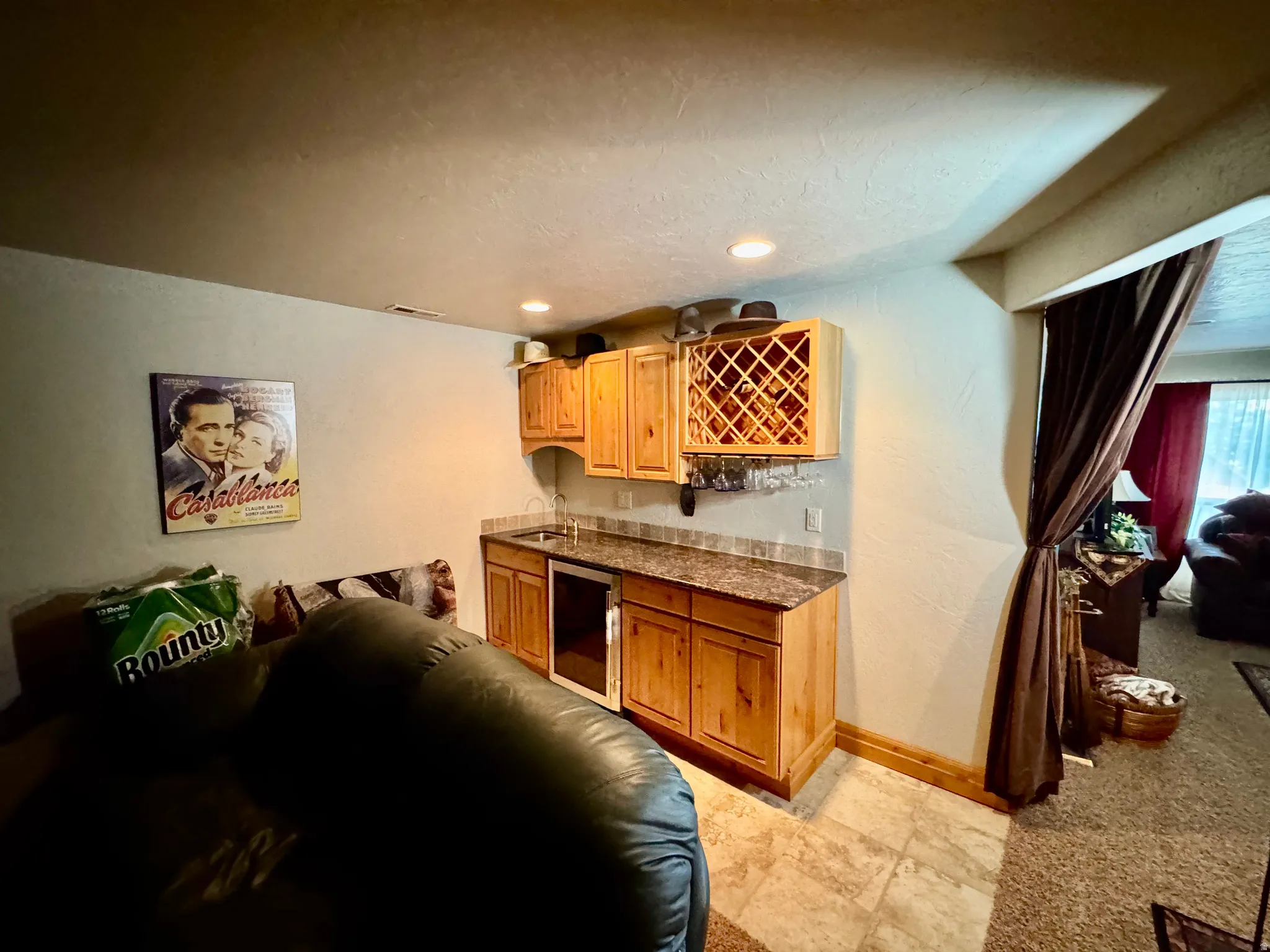 Built-in wet bar with wood cabinetry, integrated wine rack, and a compact beverage refrigerator