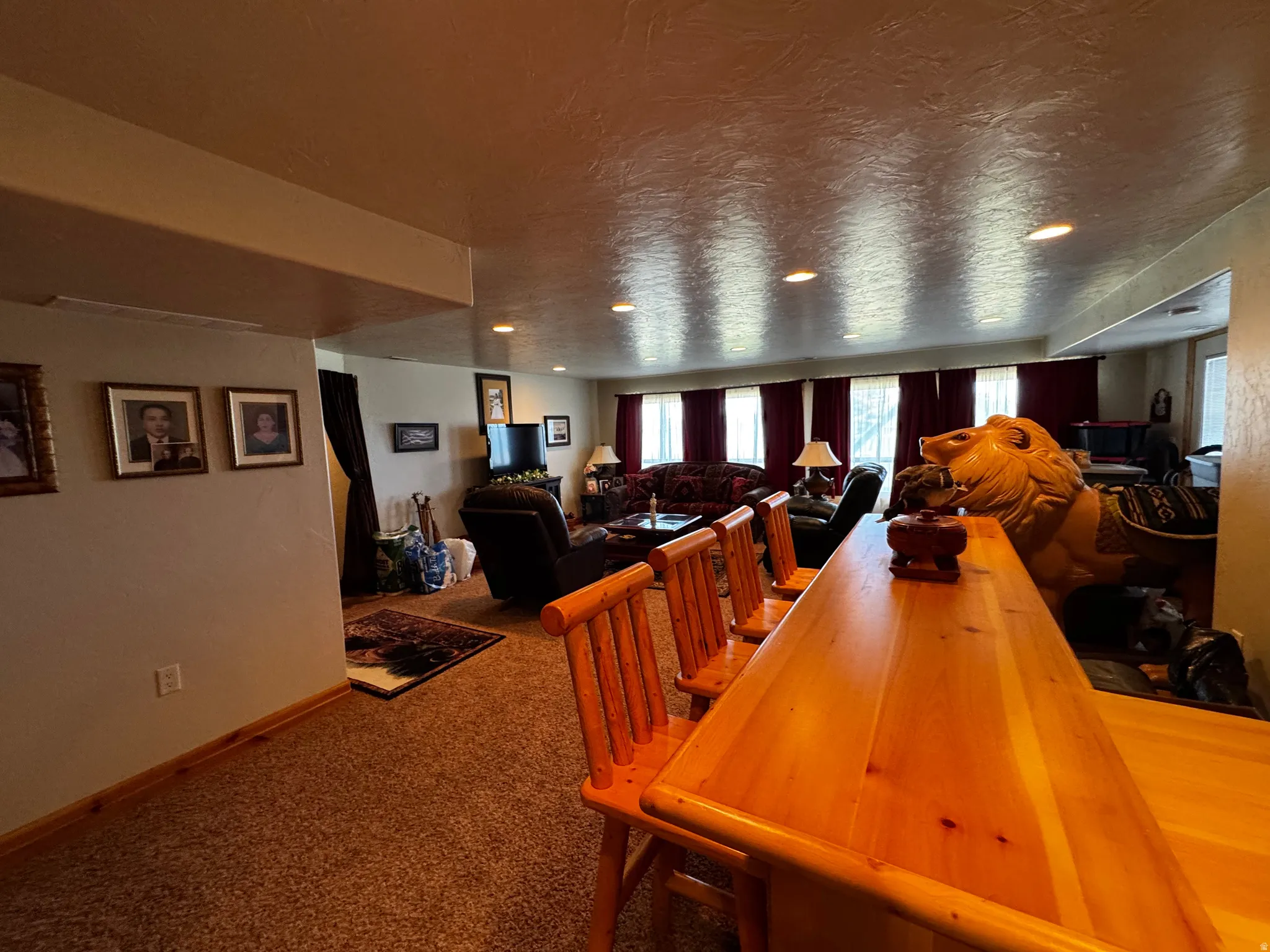 Entertainment space featuring a wood-finish bar with three wood barstools, textured carpeting, and recessed lighting