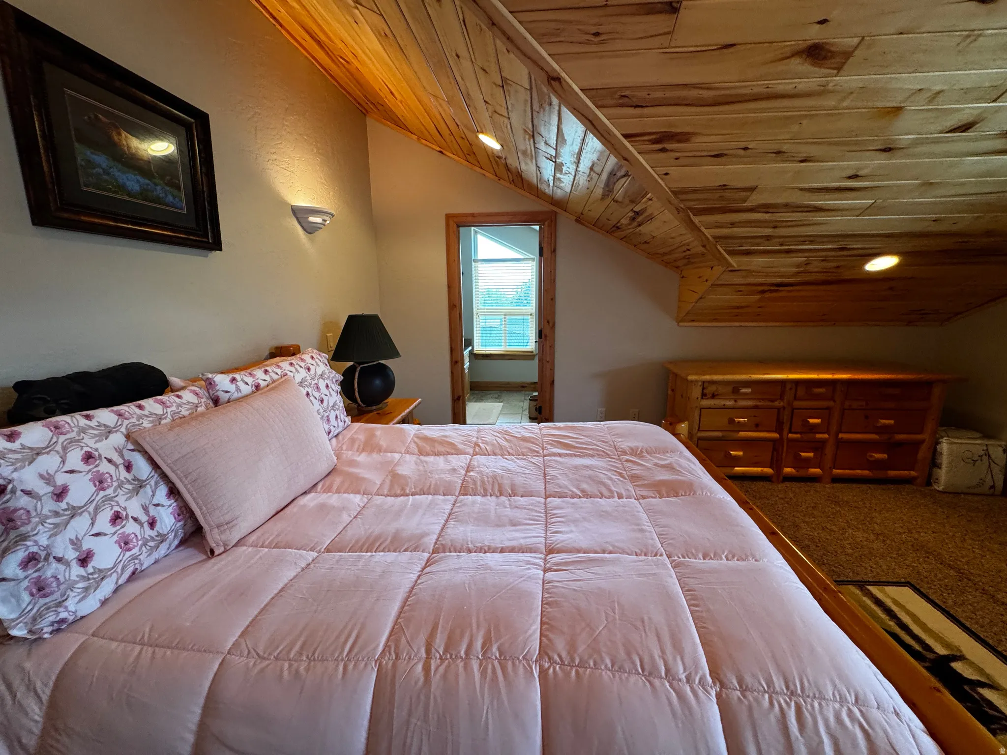 Room featuring an angled wood-paneled ceiling with recessed lighting, textured wall finishes, and wall-mounted sconce lighting