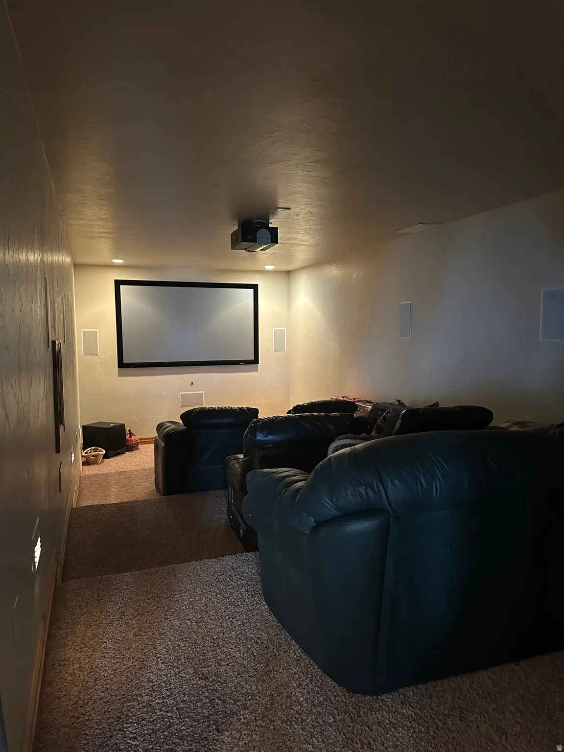 Recessed projection screen with a ceiling-mounted projector, integrated wall speakers, and recessed ceiling lighting