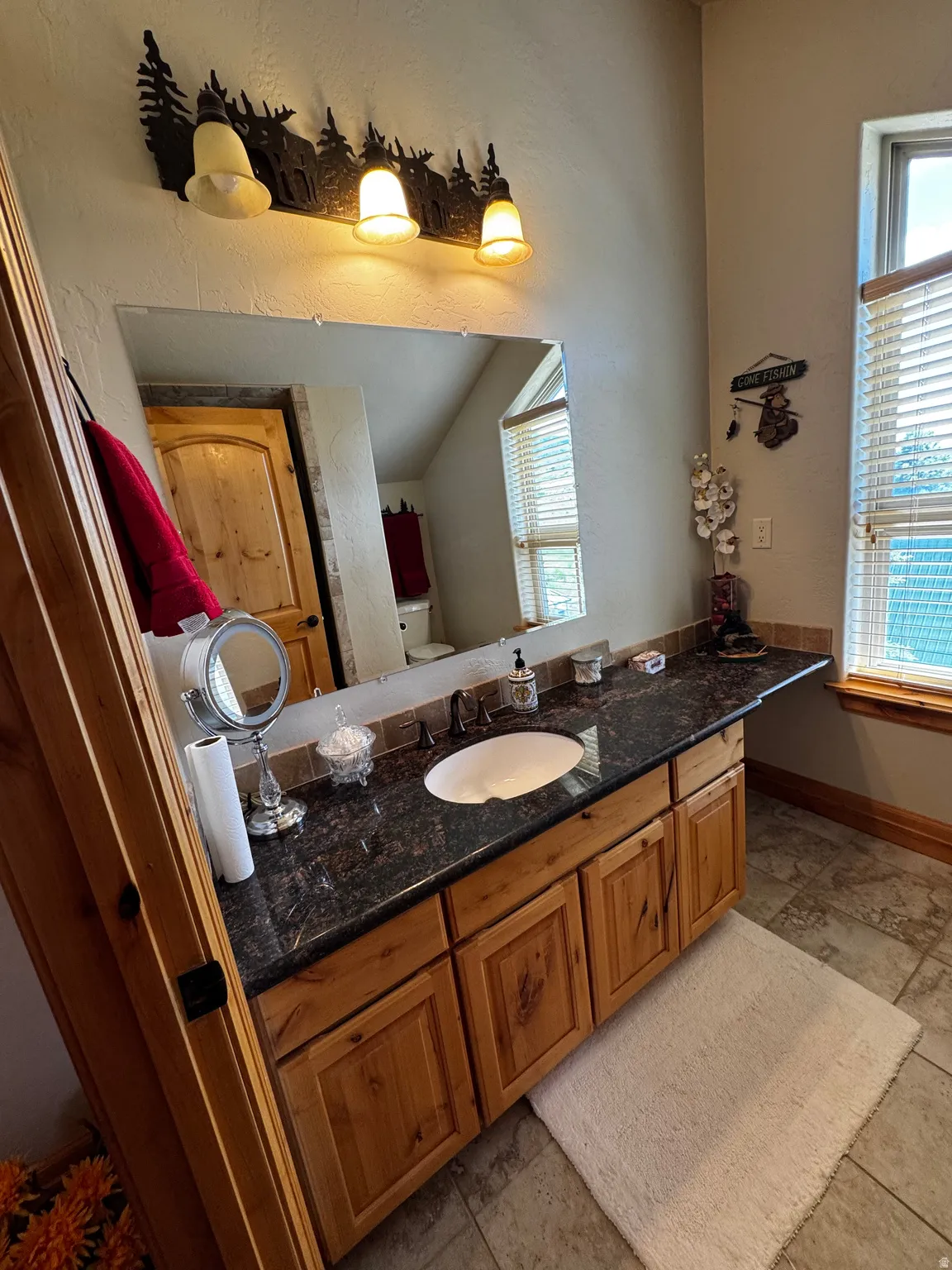Bathroom vanity featuring a dark stone countertop with an integrated sink and matte black faucet