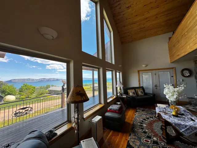 Spacious living area featuring expansive picture windows, wood-finish flooring, and an elevated wood-paneled ceiling
