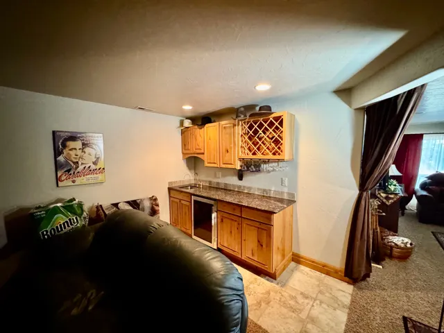 Built-in wet bar with wood cabinetry, integrated wine rack, and a compact beverage refrigerator