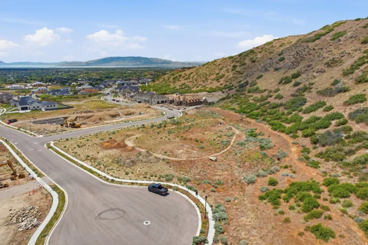 Expansive hillside development featuring new construction homes, paved roads, and a mountainous backdrop