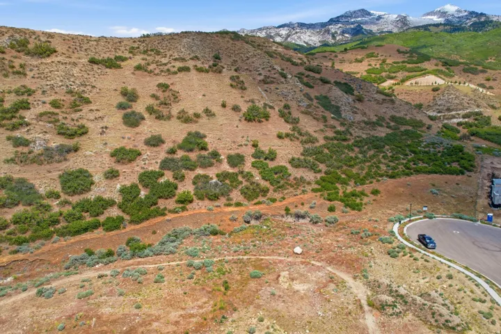 Expansive hillside property featuring natural vegetation, a paved cul-de-sac, and prominent mountain scenery
