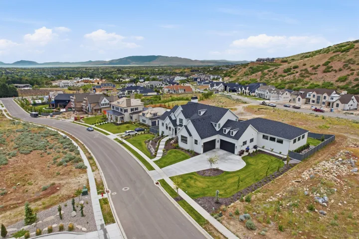 Modern farmhouse architecture featuring a crisp white exterior, dark pitched roofs, and multiple dormer windows