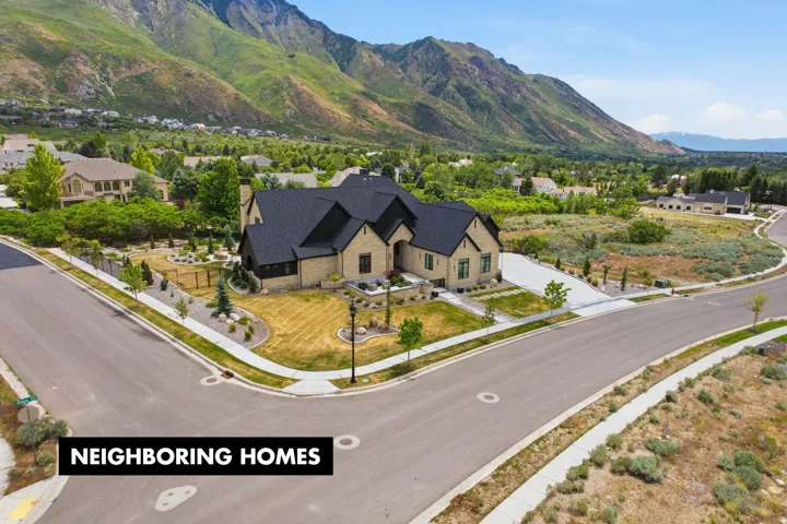 Stone exterior residence with a dark shingle roof, established landscaping, a concrete driveway, and a corner lot position