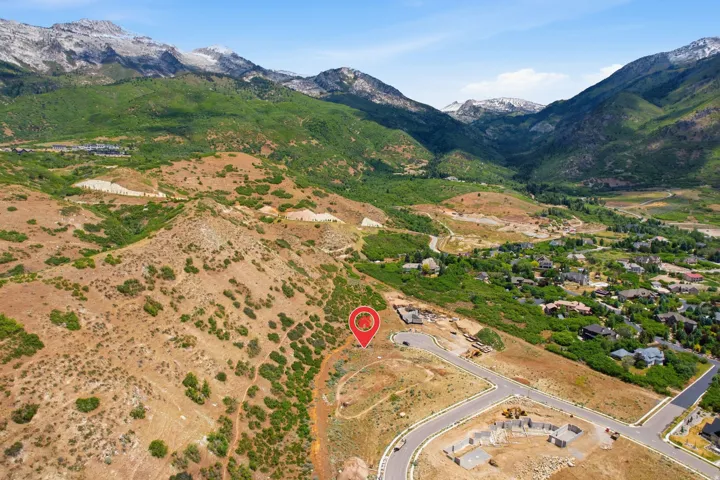 Expansive building site featuring mountain terrain, surrounding green foliage, and a curved paved road