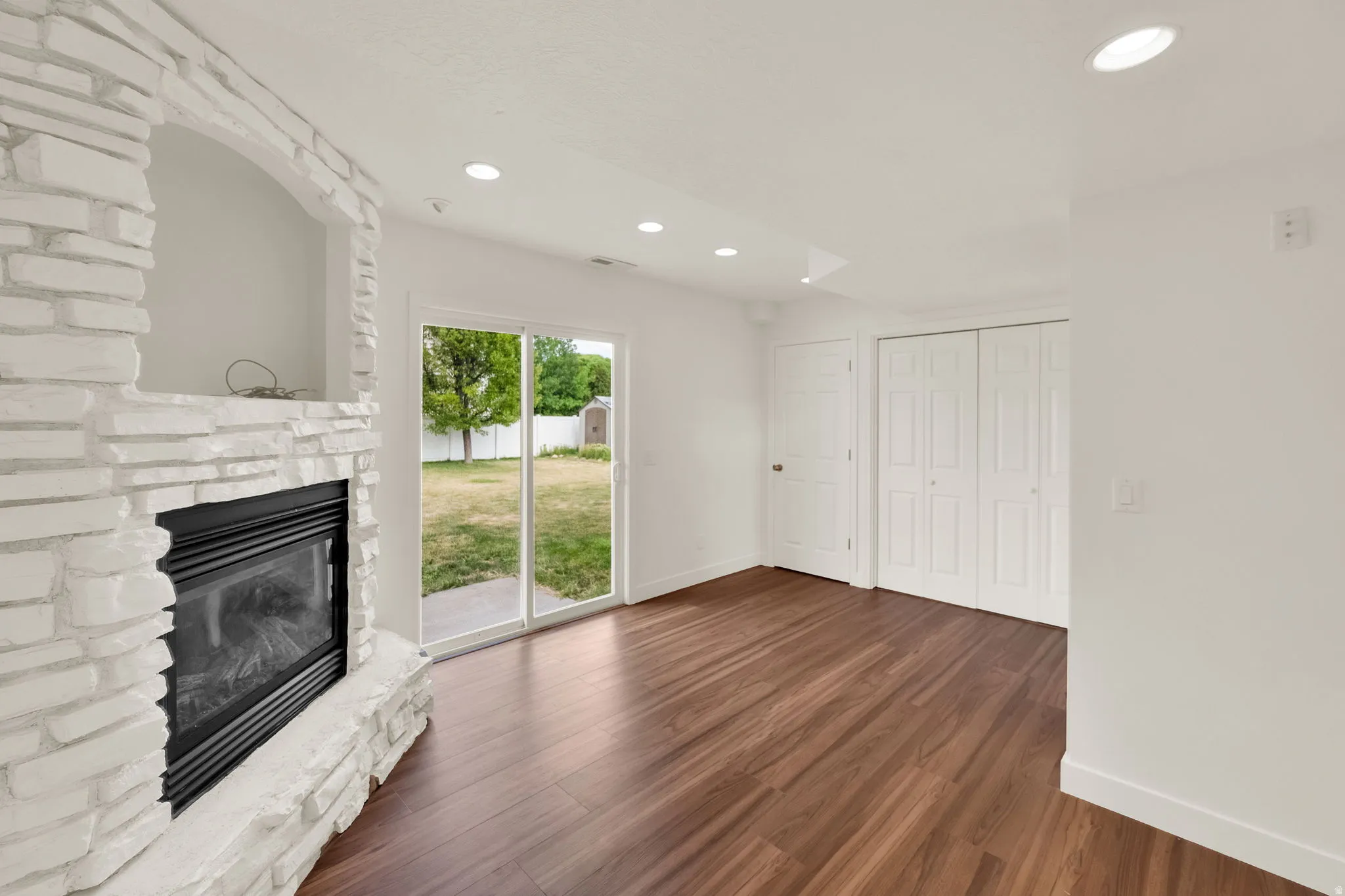 White stacked stone fireplace with an integrated hearth and dark wood-finish flooring