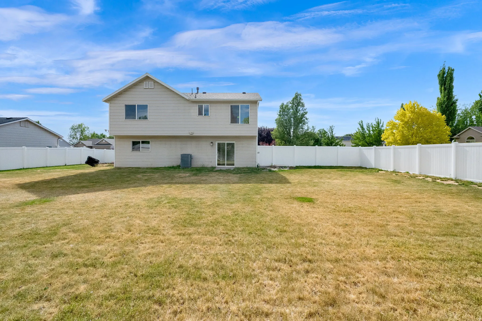 Expansive backyard space framed by a white privacy fence