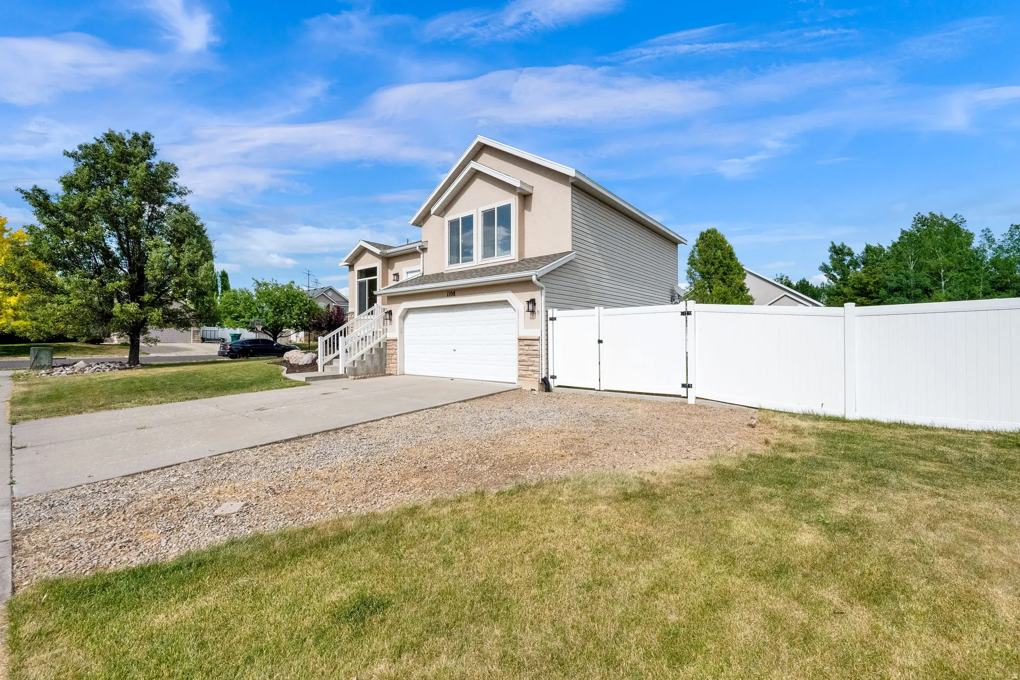 Contemporary two-story residence featuring stucco and siding exterior, an attached two-car garage, and a white vinyl fence