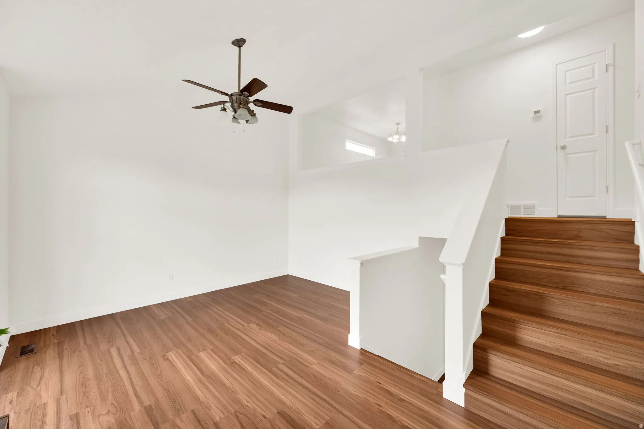 Open-concept living space featuring wood-finish flooring, a contemporary ceiling fan, and a bright white interior