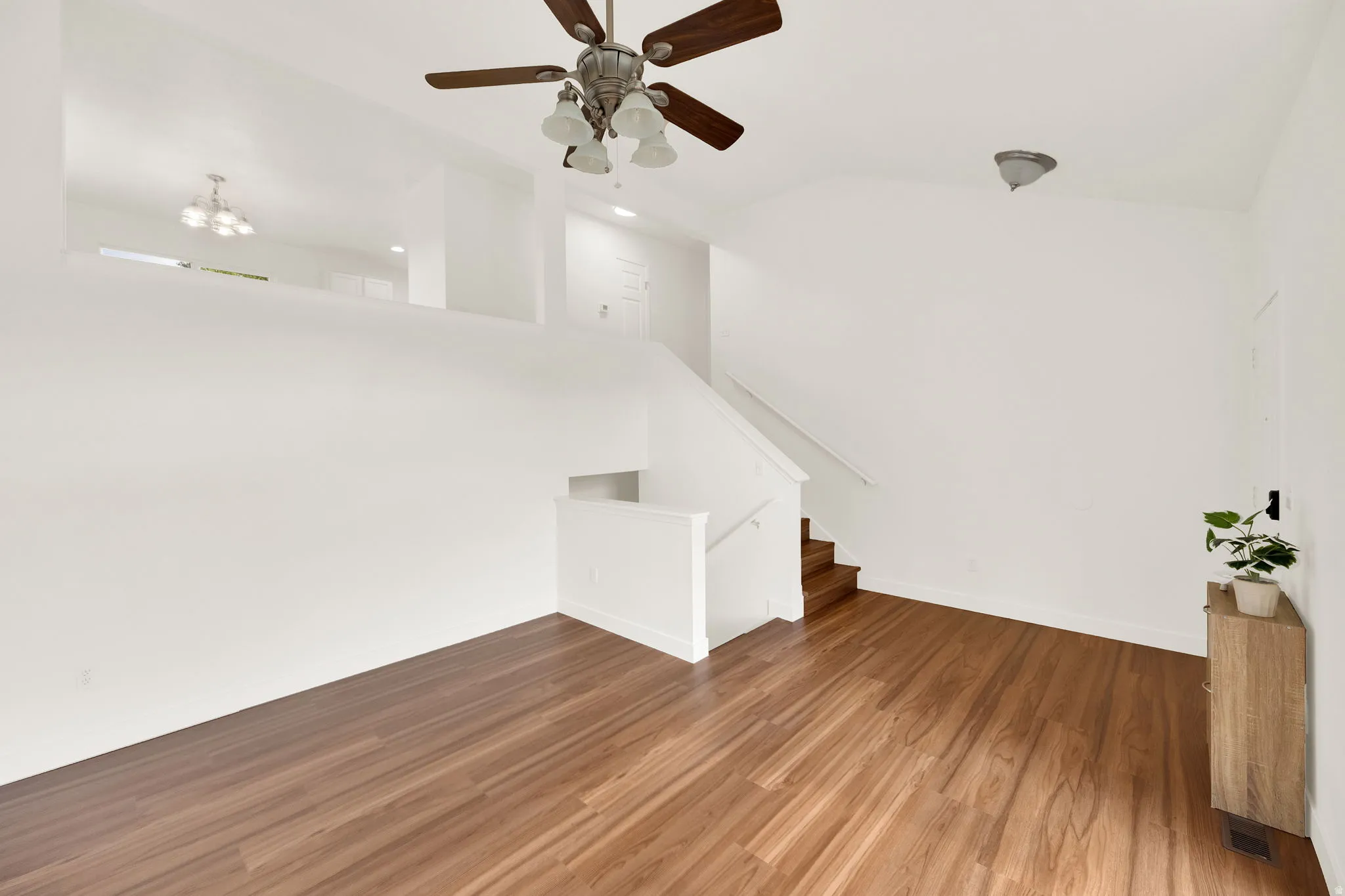Open-concept living space featuring wood-finish flooring, a contemporary ceiling fan, and a neutral color palette