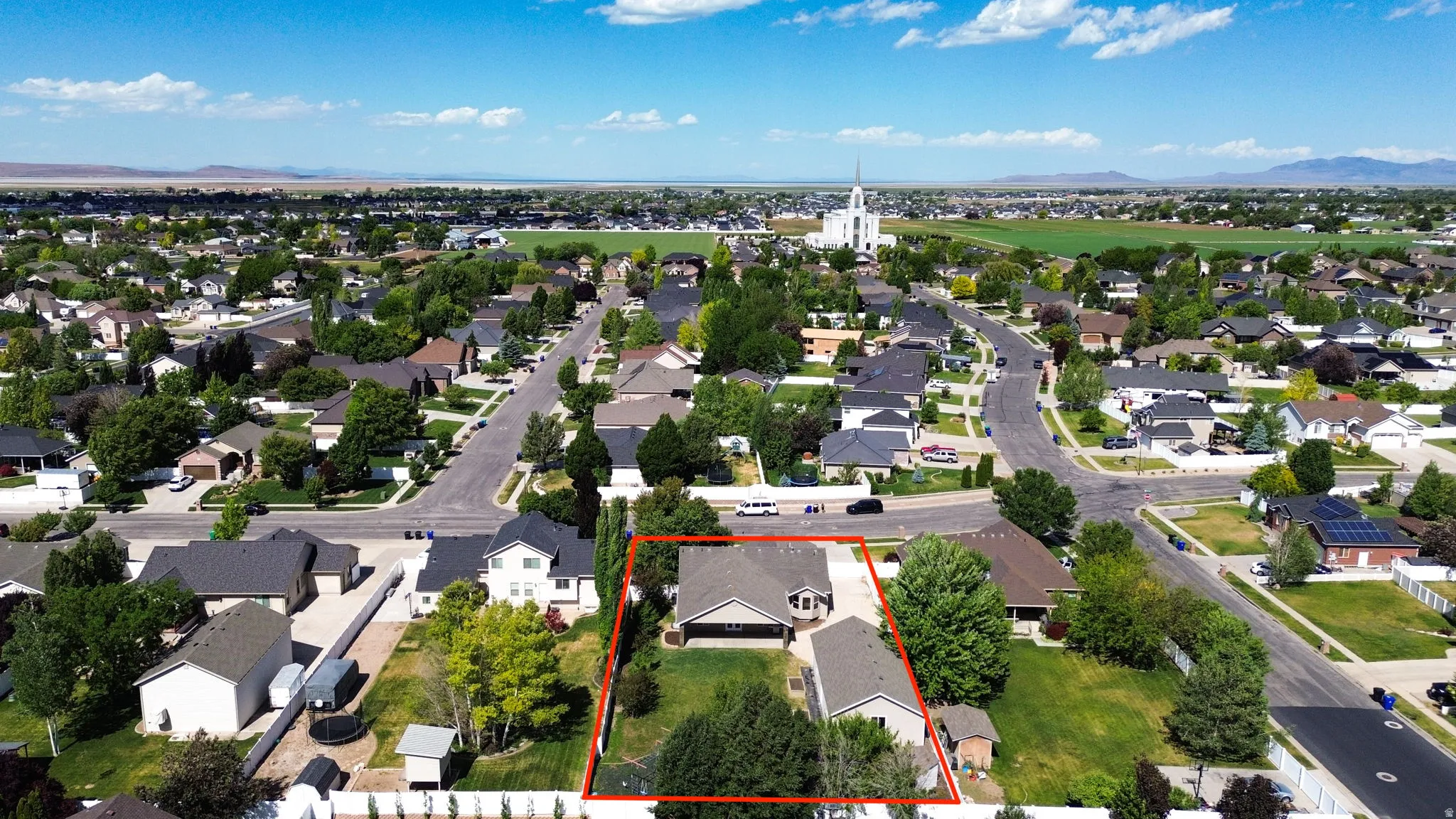 Aerial view of a residential property with an expansive green lawn and mature trees