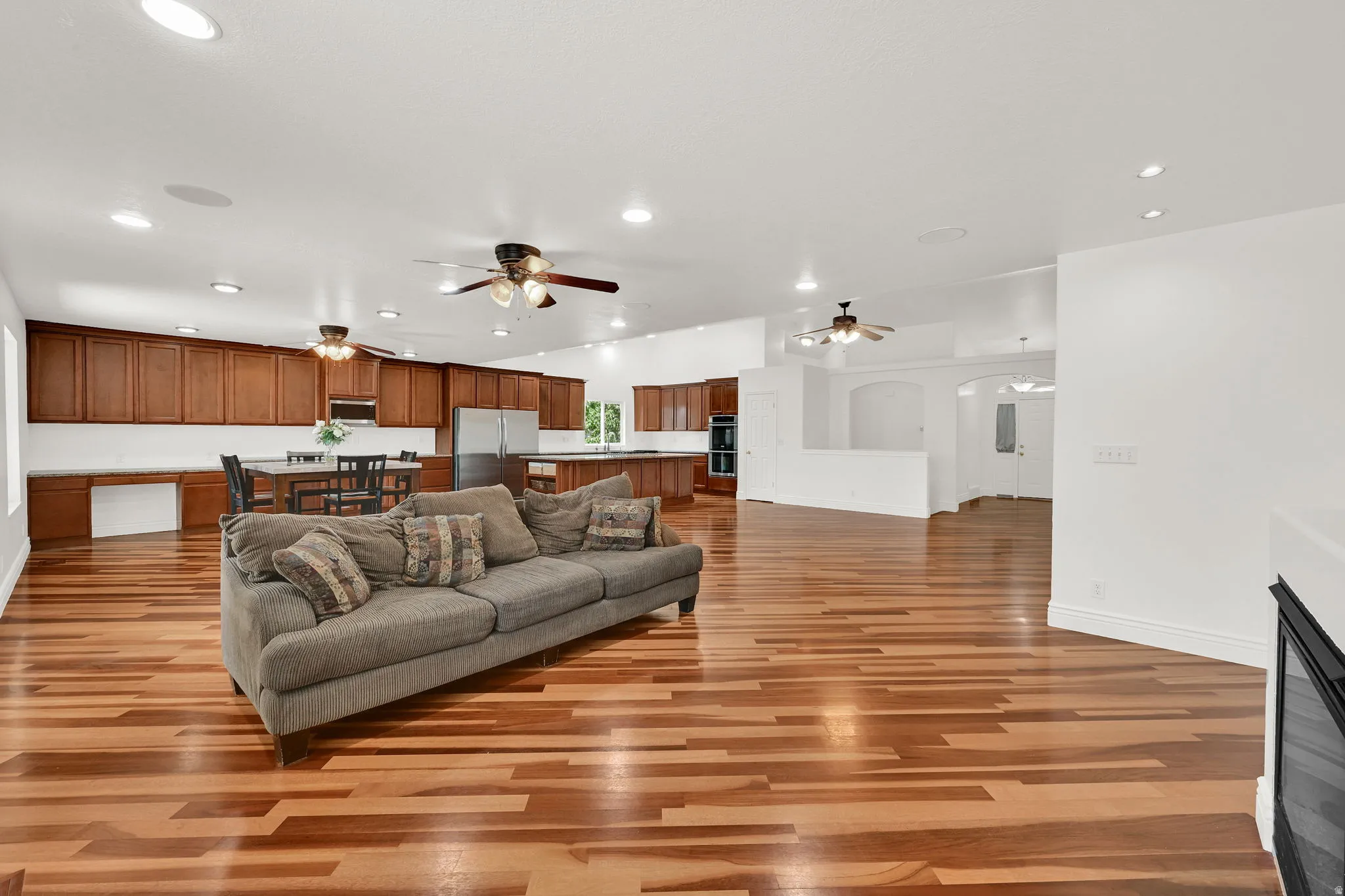 Spacious open-concept living area featuring wood-finish flooring, recessed lighting, and ceiling fans