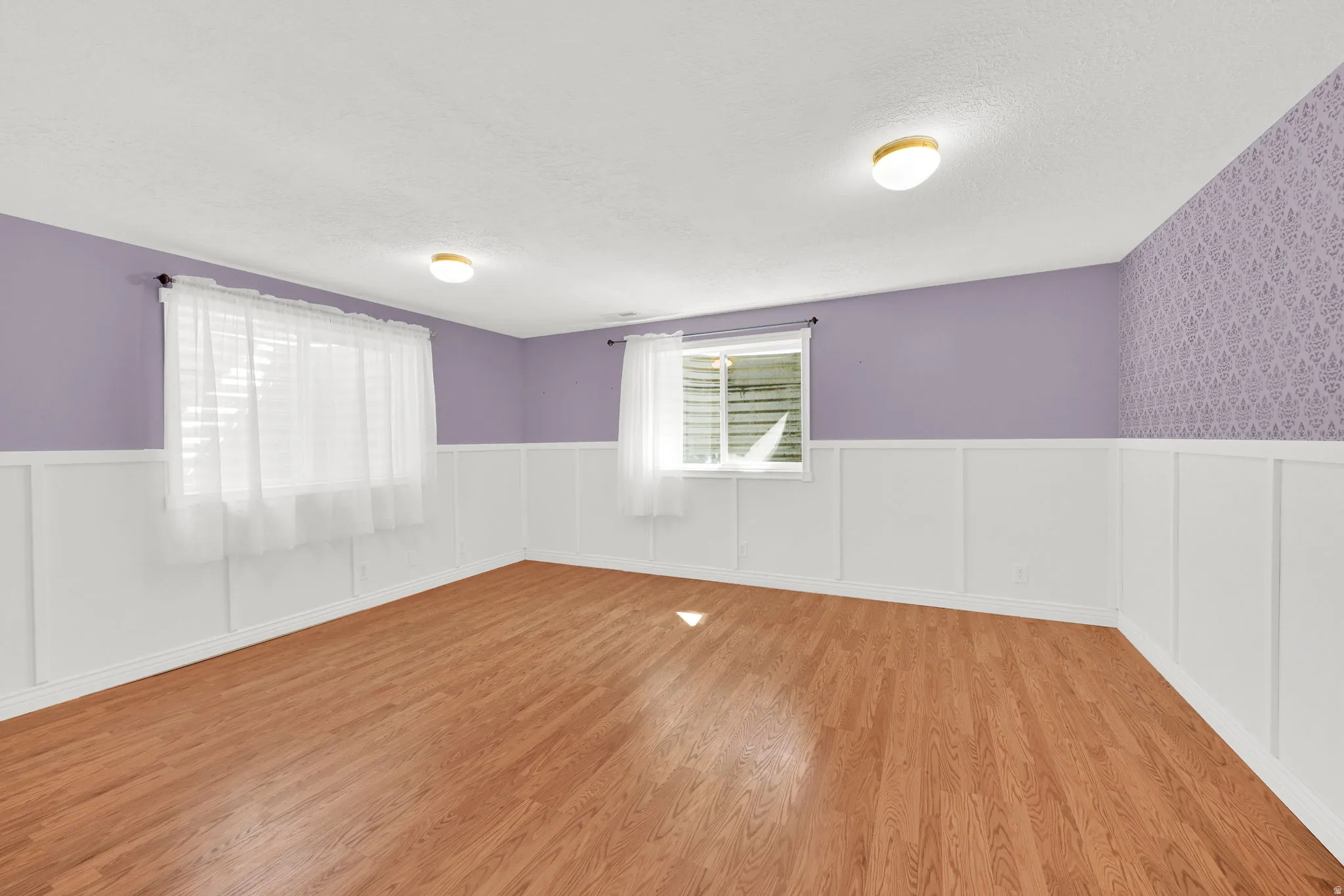 Wood-finish flooring throughout, complemented by white wainscoting and lavender-painted walls