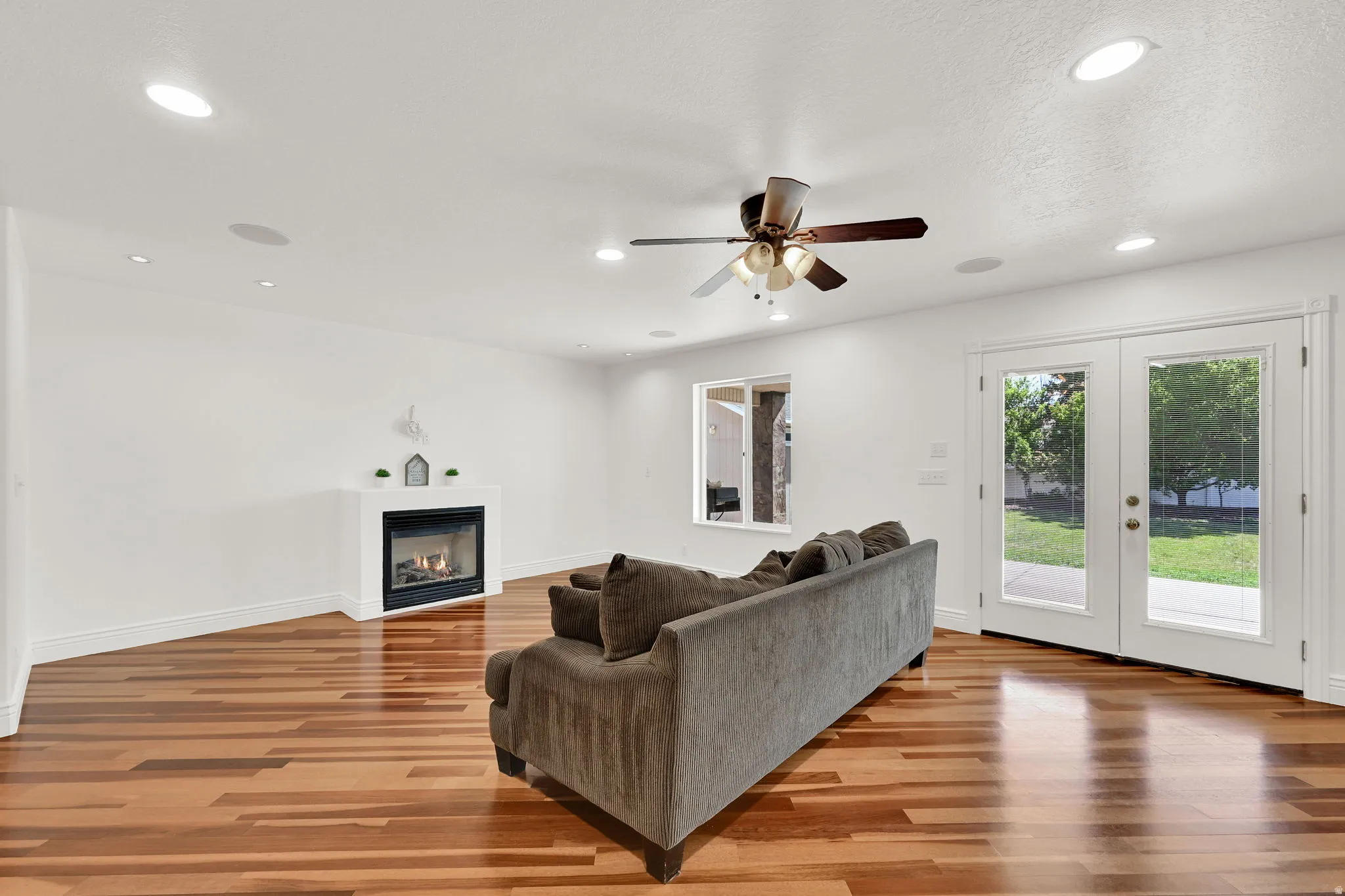 Spacious living area featuring wood-finish flooring, a modern fireplace, and recessed lighting