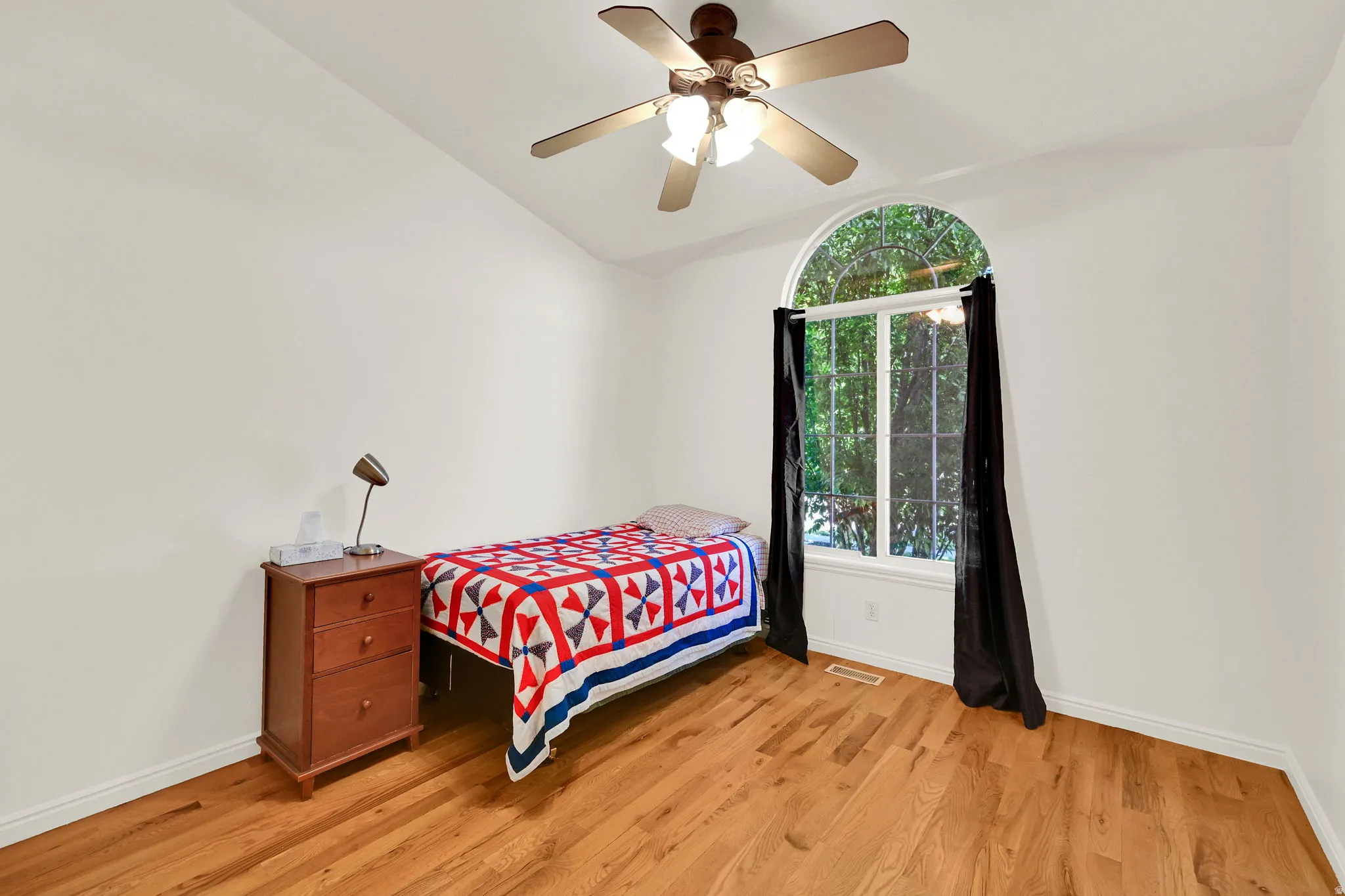 Room featuring light wood-finish flooring, a vaulted ceiling, and white wall finishes