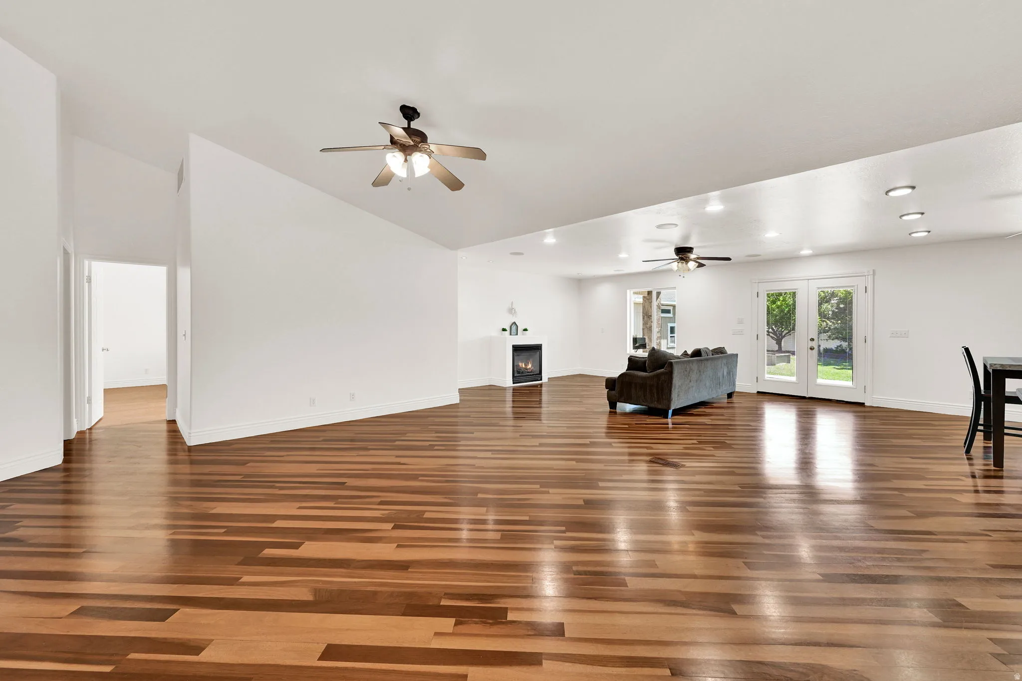 Spacious room with wood-finish flooring, white walls, and a vaulted ceiling