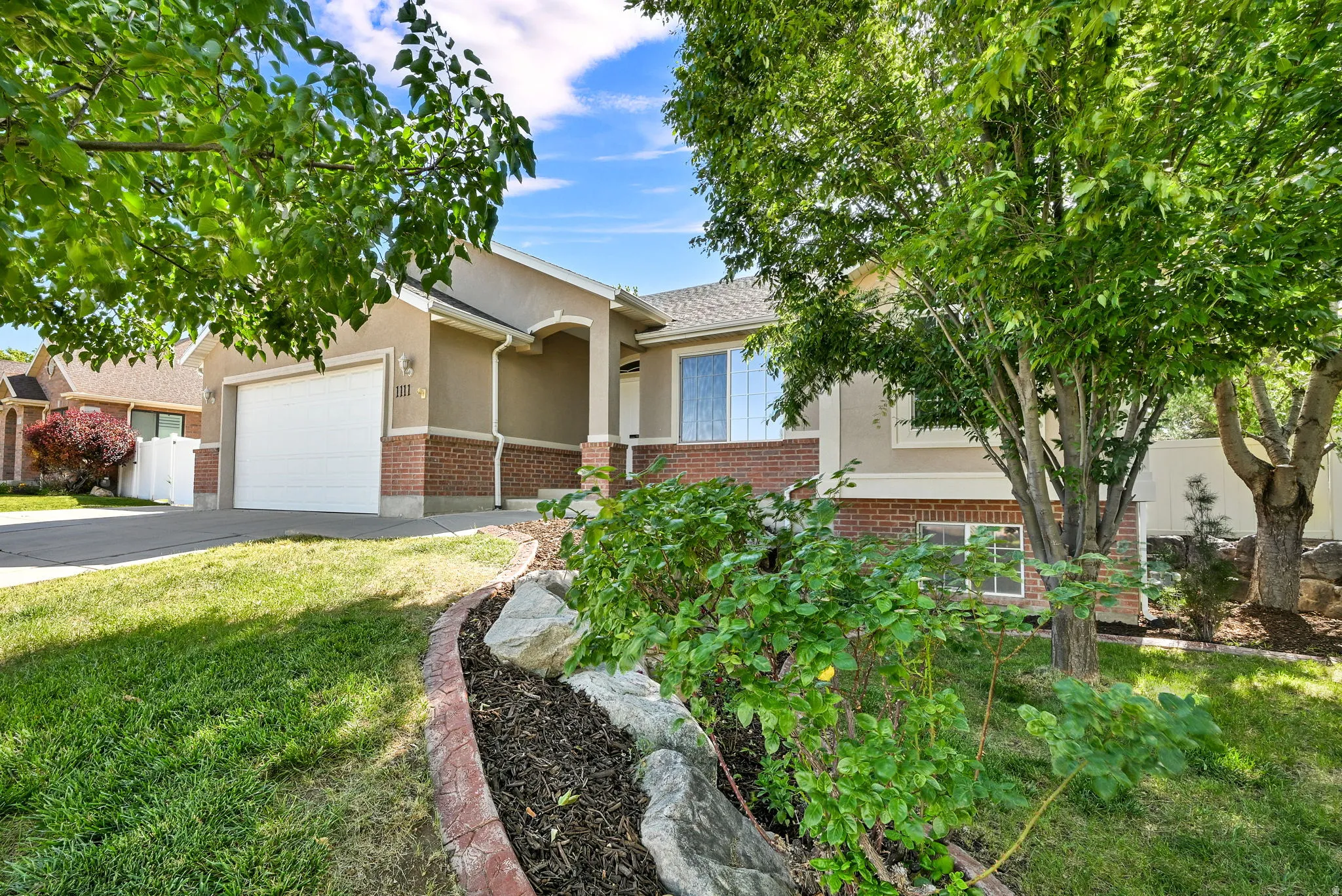 Exterior featuring a two-car garage, brick accents, and a stucco finish