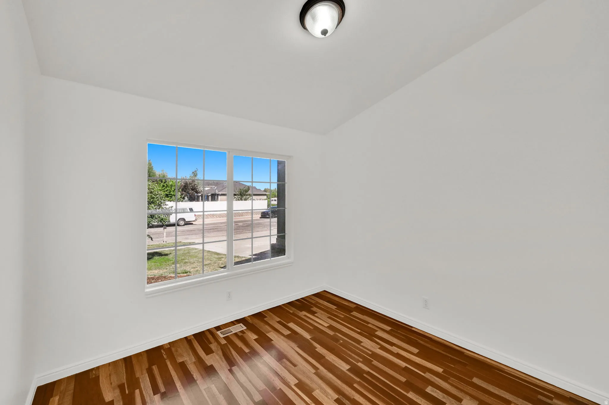 Bright room with wood-finish flooring, white walls, and a multi-pane window