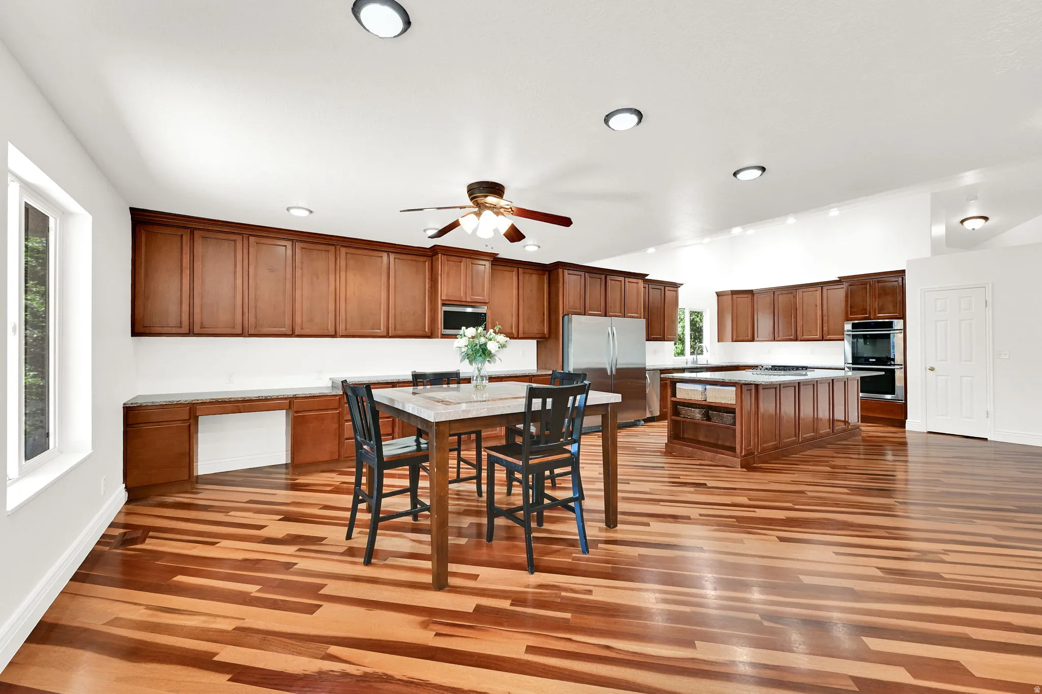 Spacious kitchen featuring extensive wood cabinetry, stainless steel appliances, a large center island, and wood-finish flooring